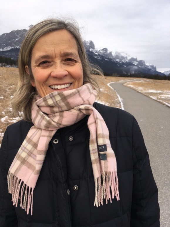 Dr. Karen Beauchemin walks along a trail with the Rocky Mountains behind her