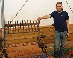 A scientist stands next to a piece of farm equipment.