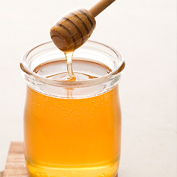 Cuillère à miel sort une coulée de miel d'un pot en verre rempli