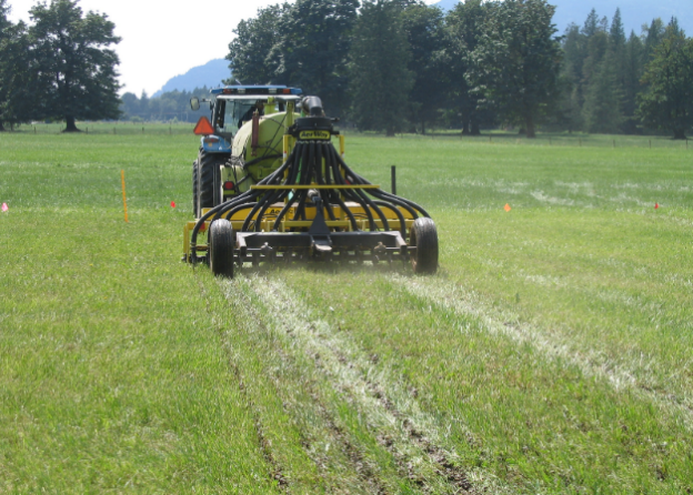 Une machine à cercler applique en surface la boue liquide séparée dans un champ d’herbe.