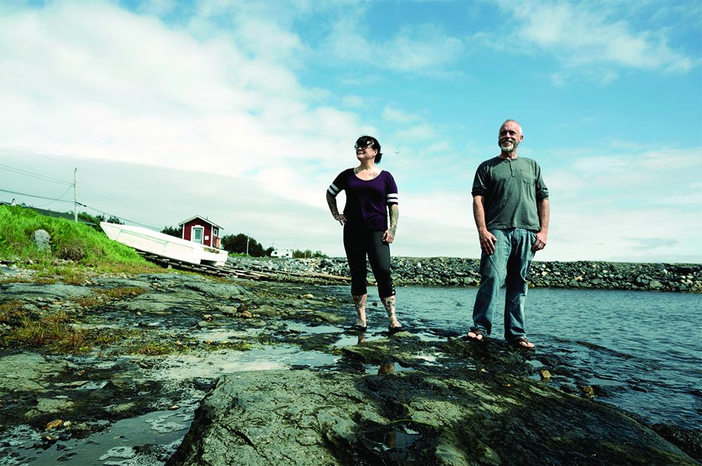 Ben Wiper and a team member stand near a body of water and look towards the camera