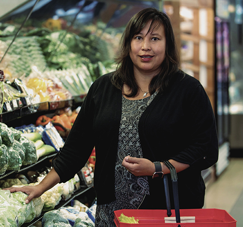 Une femme choisissant des légumes dans un marché d'alimentation