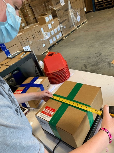 A worker takes measurements of a box filled with health care supplies