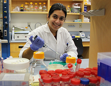 Ph.D. student Nishat Islam working and smiling in the laboratory