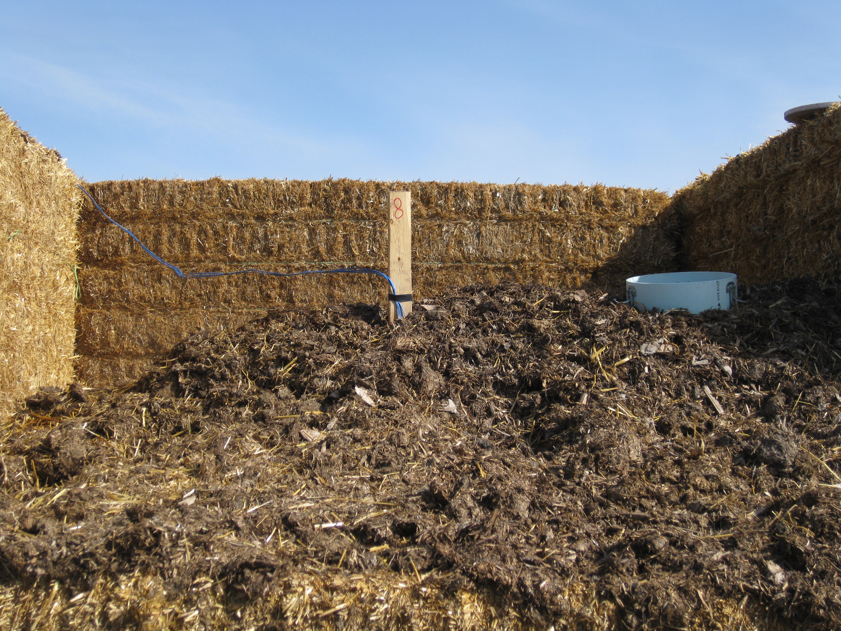 Large straw bales of hay acting as barrier to manure.