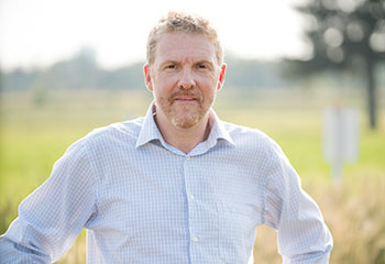 An upper body portrait of Dr. Andrew Davidson standing in a field.