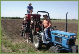 Farmers with a tractor pulling standard seeding equipment.