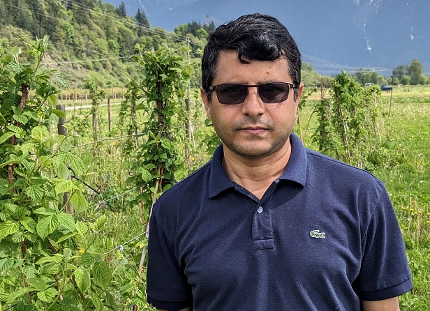 Dr. Rishi Burlakoti stands in front of a row of raspberry plants