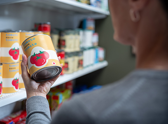 A person holding a can of tomato sauce with small maple leaf