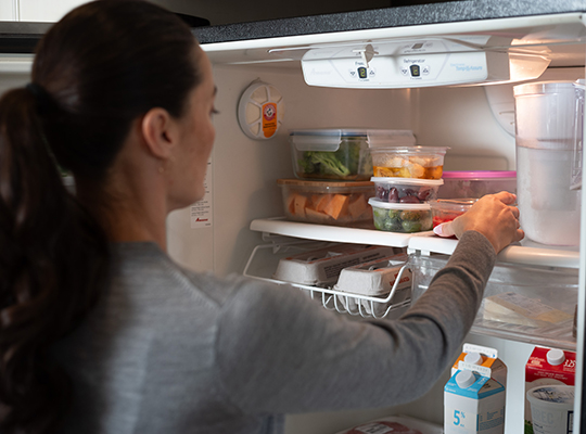 A person storing food in a refrigerator