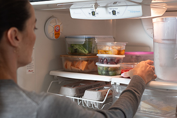A person storing food in a refrigerator.
