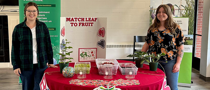 Two women pictured at a booth with a display of strawberries.