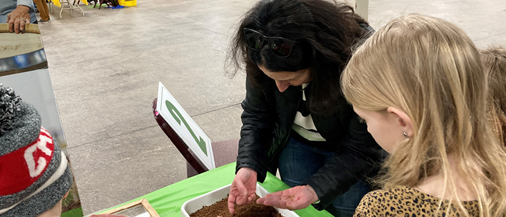 A woman showing an insect to students.