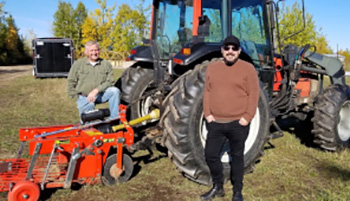 Two people standing next to a large tractor