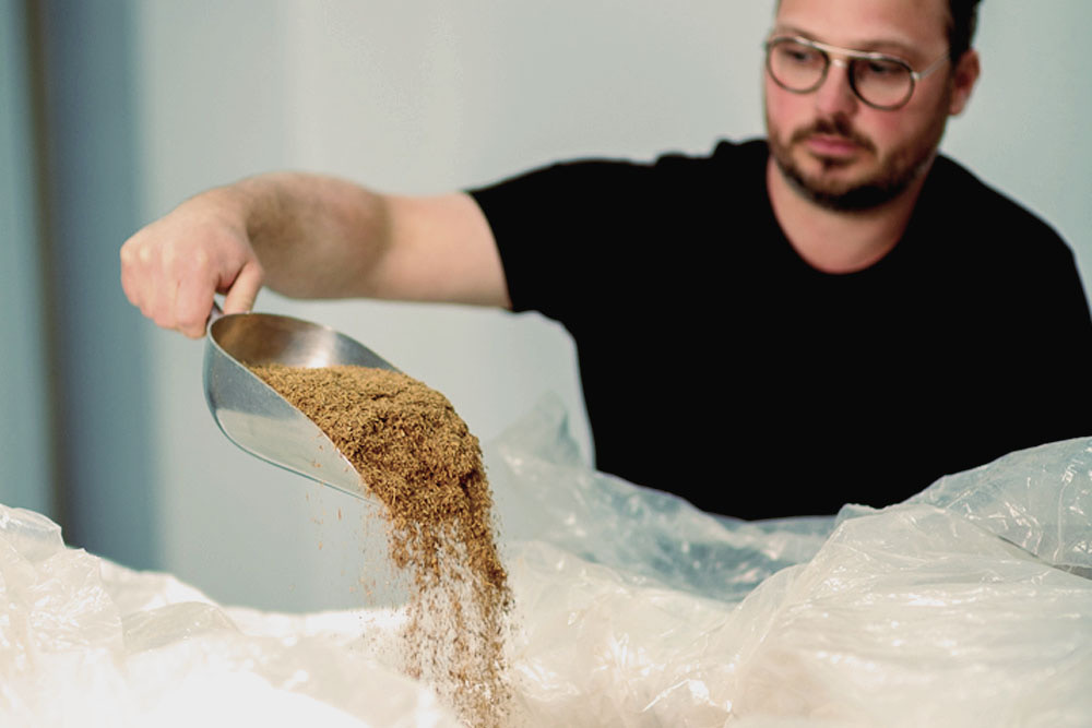 Jonathan Rodrigue pouring spent grain into a bag