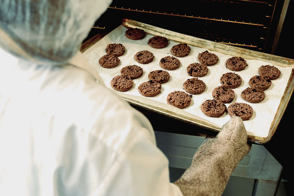 An employee taking out a tray of cookies from the oven