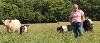 A farmer standing in a field with cows and a fence in the background