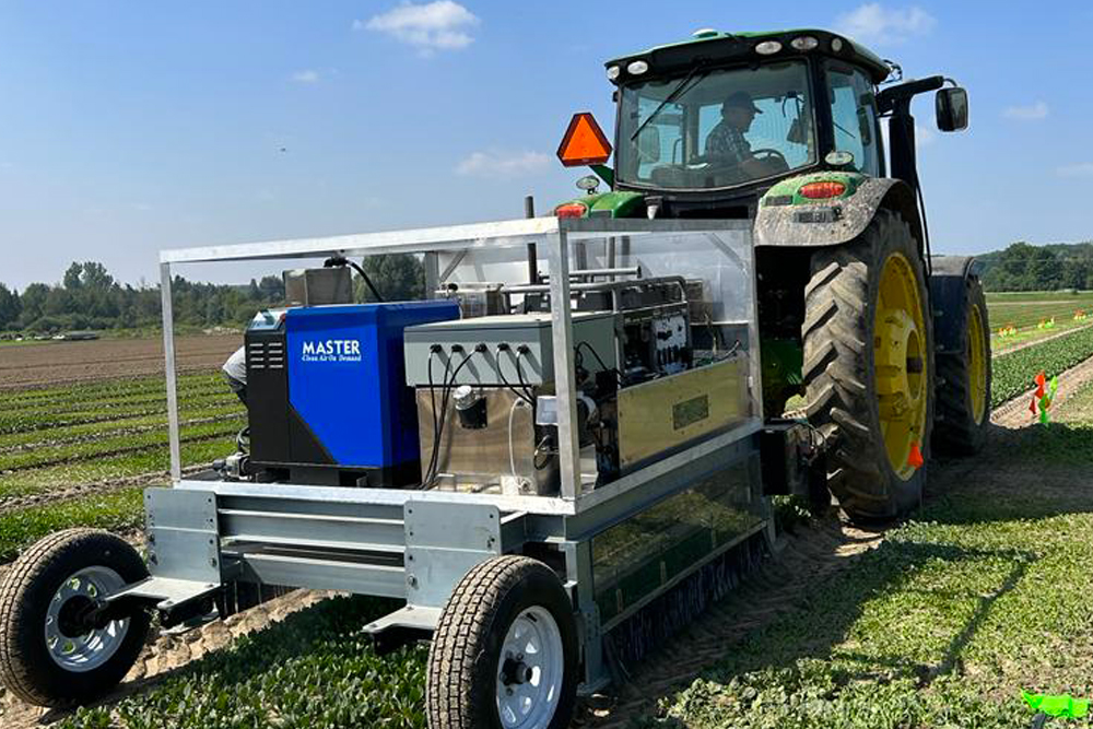 A tractor transporting Clean Works technology over spinach.