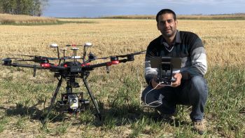 Male scientist kneeling next to drone