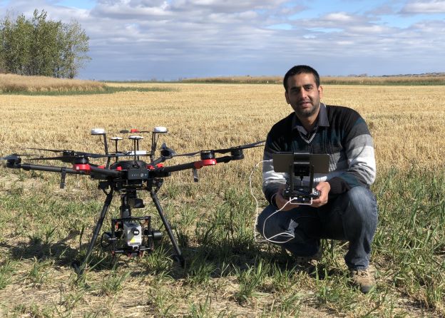 Male scientist kneeling next to drone